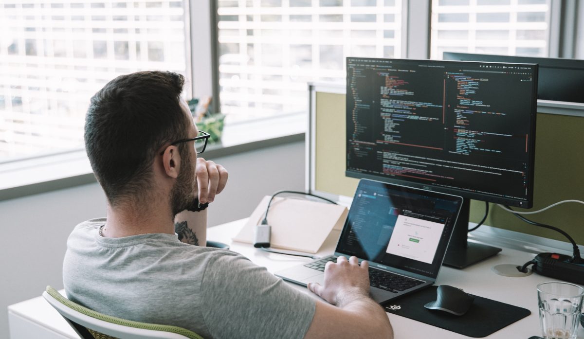 Rozwój aplikacji iOS MacBook z Xcode edytujący Swift kod aplikacji iOS z podglądem iPhone'a